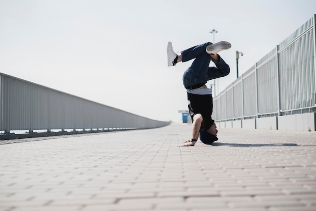 A young male person doing headstand outdoors