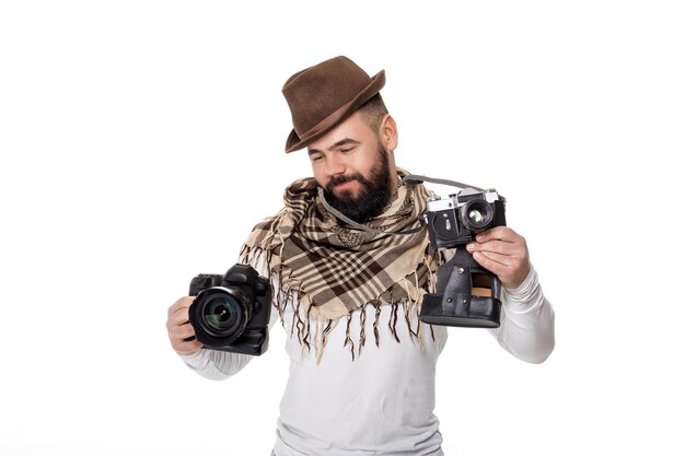 Young male photographer chooses between retro camera and digital camera on white background