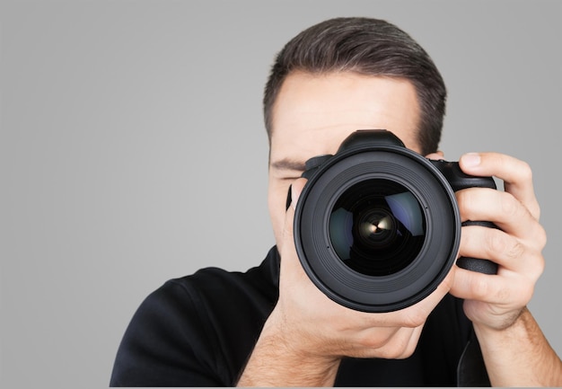 Giovane fotografo maschio che osserva tramite la macchina fotografica