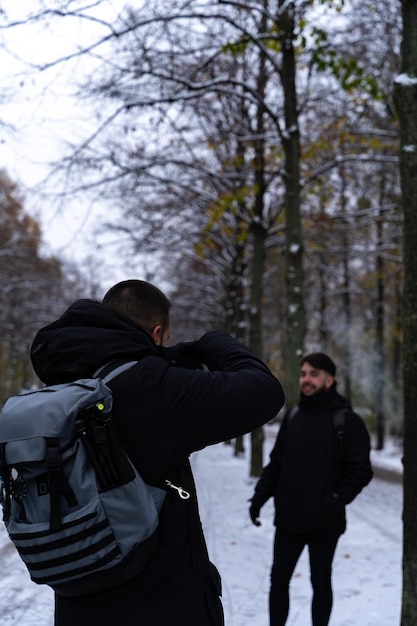 Фото Молодой фотограф-мужчина фотографирует модель или туристов в парке тиргартен в берлине