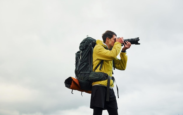 Young male photographer with his professional camera taking pictures of beautiful nature