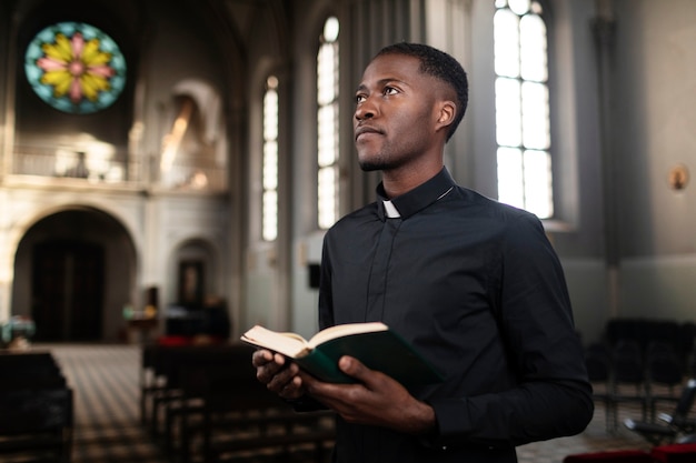 Giovane sacerdote maschio che tiene il libro sacro nella chiesa