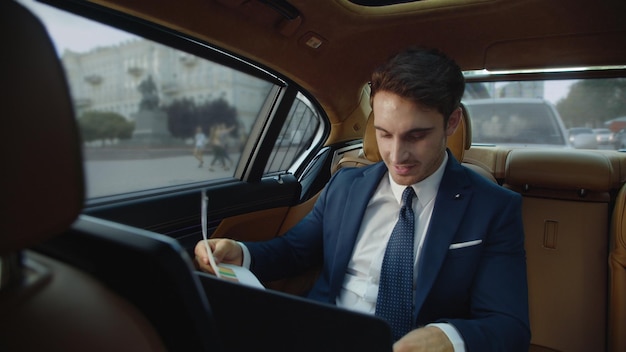Photo young male professional looking at data documents in business car man in car