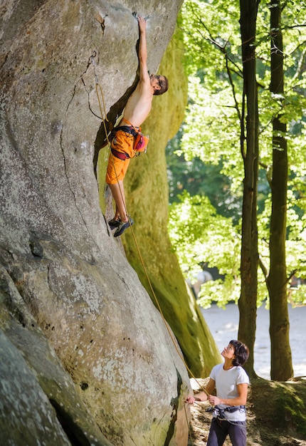 Young male rock climber reaching for the next grip while lead cl