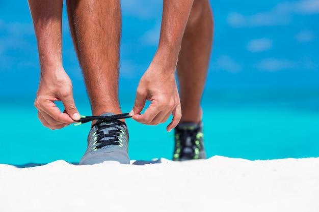 Giovane corridore maschio che si prepara per iniziare sulla spiaggia bianca