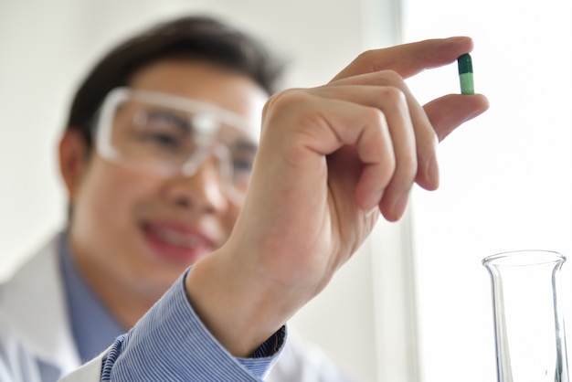 Young male scientist holding a pill. 