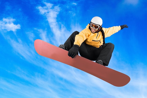 Young male snowboarder jumping on sky background at wintertime