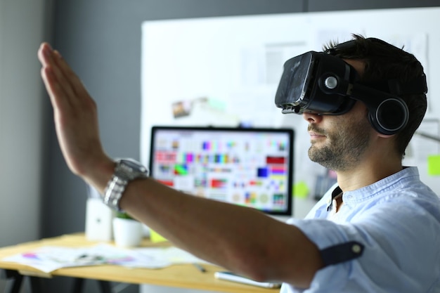 Foto giovane programmatore di software maschile che testa una nuova app con occhiali per realtà virtuale 3d in ufficio