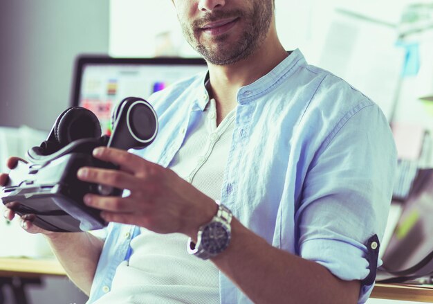 Young male software programmer testing a new app with 3d virtual reality glasses in office