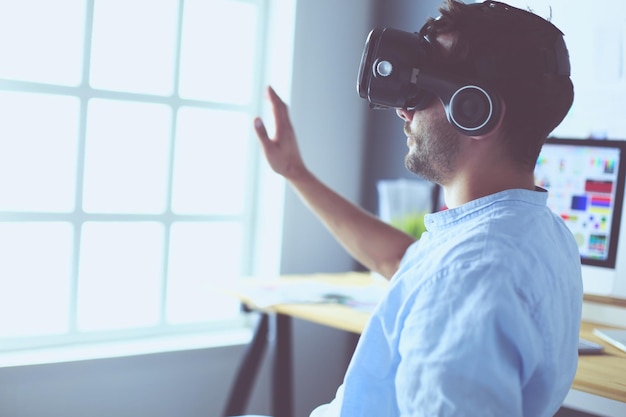 Young male software programmer testing a new app with 3d virtual reality glasses in office