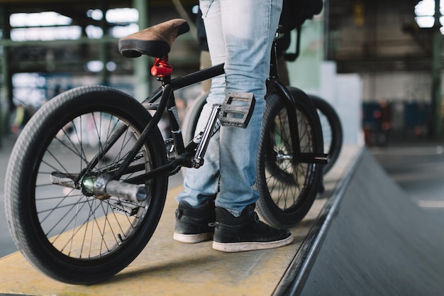 Giovane maschio che resta con la sua bici sulla rampa piloti bmx irriconoscibili