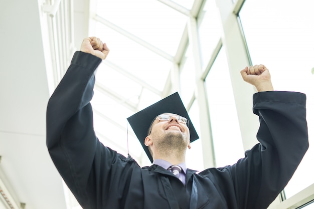 Foto giovane studente maschio in abito nero laurea