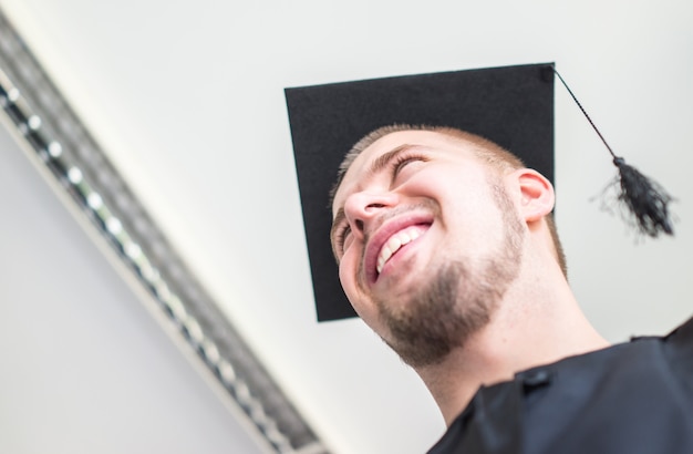 Young male student in black graduation gown