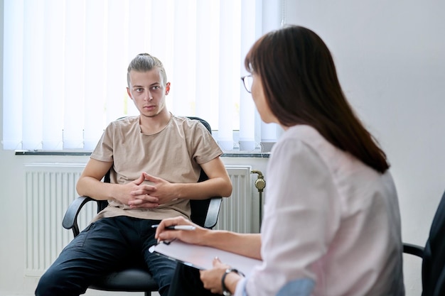 young male student at therapy meeting with college psychologist counselor