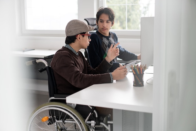 Young male student in wheelchair working on computer