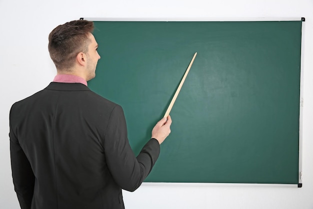 Young male teacher beside blackboard on white blackboard