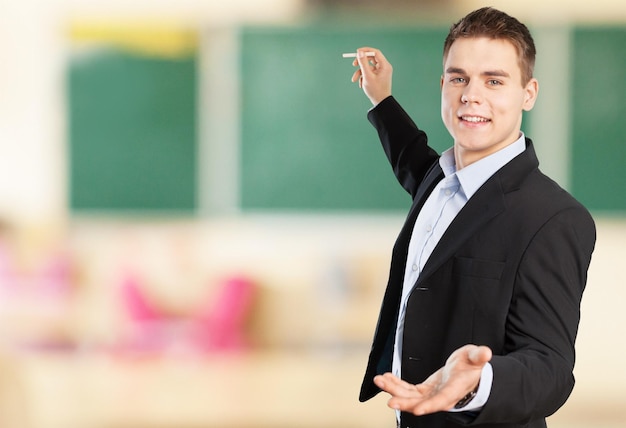 Young male teacher   standing  on background