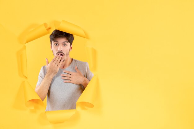 young male on torn yellow paper background facial guy handsome