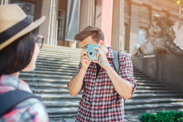 Young male tourist stand at steps and take pictures of woman
