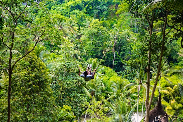 Young male tourist swinging on the cliff in the jungle