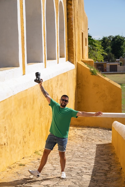 Photo young male tourist with camera entering the convent of san antonio in izamal mexico