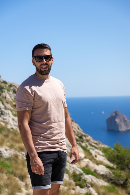 Young male tourist with sunglasses at the viewpoint es Colomer in Mallorca Spain