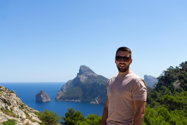 Young male tourist with sunglasses at the viewpoint es Colomer in Mallorca Spain