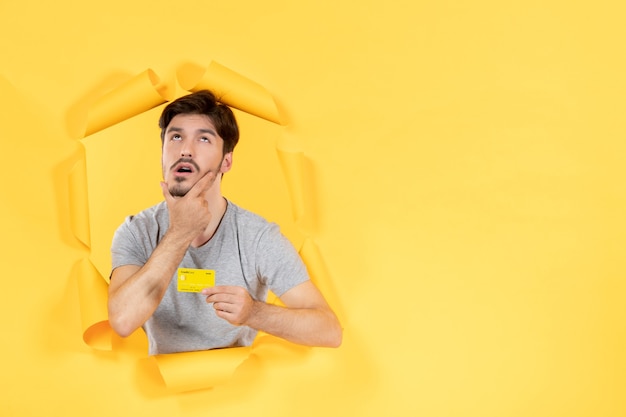 young male with credit card on torn yellow paper background money bank sale