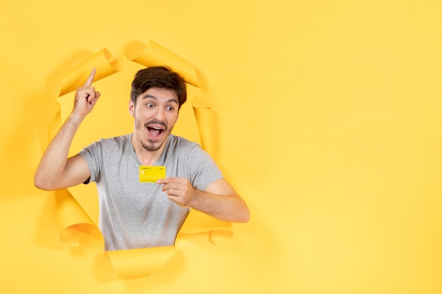 young male with credit card on the yellow paper background money bank sale shopping