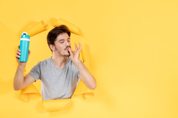 young male with green bottle on yellow background fit gym workout