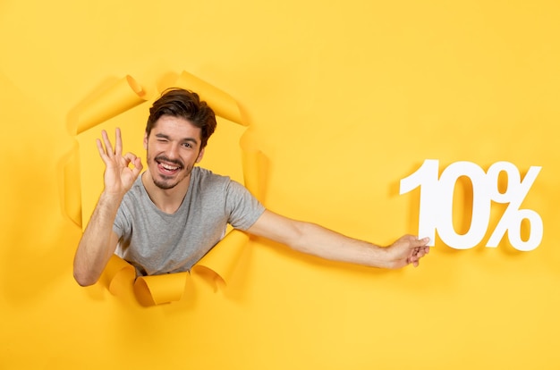 Young male with inscription sign on the torn yellow paper background shopping guy sale