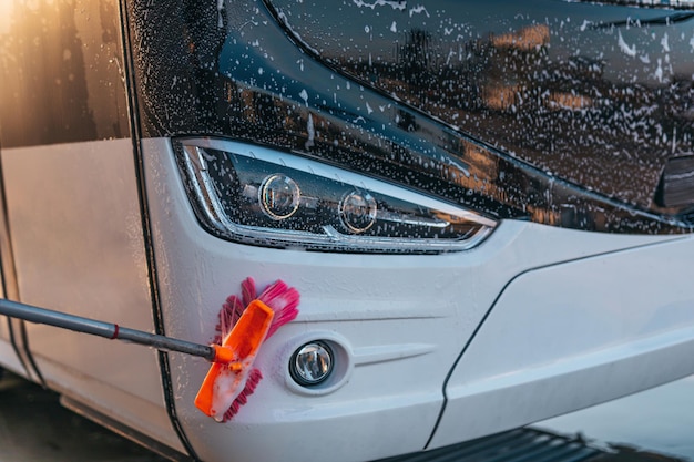 Young male worker washing bus.