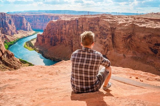 Молодой человек любуется потрясающим видом на плотину Глен-Каньон и реку Колорадо в Пейдж, штат Аризона.