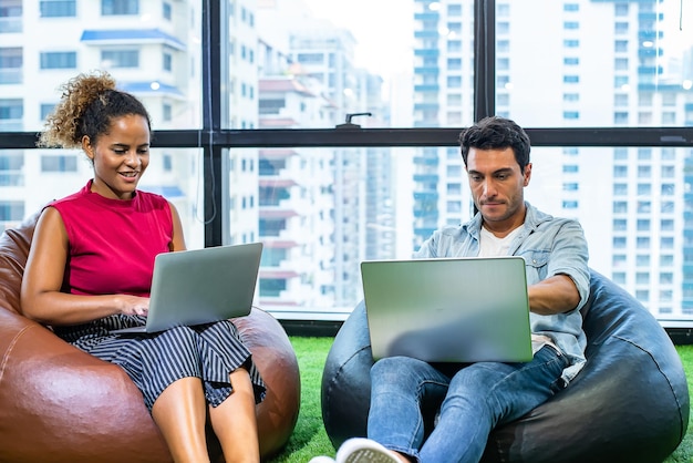 Young man and african woman use notebook in modern office