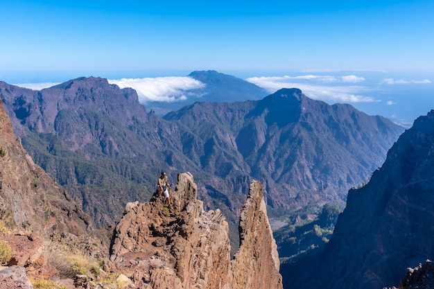 ロケデロスムチャチョス近くのカルデラデタブリエンテの火山の頂上でトレッキングを終えた若い男性。カナリア諸島のラパルマ島のすばらしい風景を眺めています。スペイン