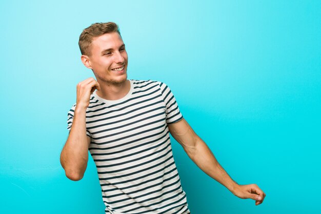 Young man against a blue wall dancing and having fun