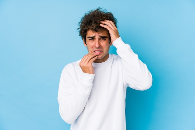 Young man against a blue whining and crying disconsolately.