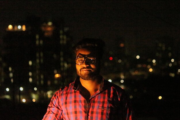 Photo young man against illuminated city at night