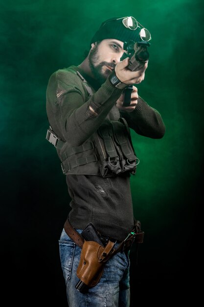 Photo young man aiming rifle while standing against green smoke