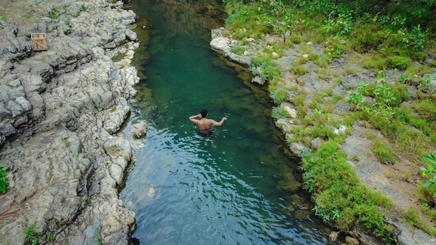 きれいで美しい川で一人で泳ぐ若い男性