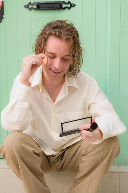 A young man applies makeup