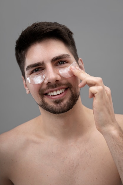 Photo young man applying anti-dark circle pads