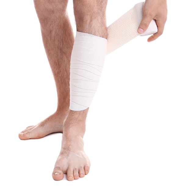 young man applying bandage onto leg on white background
