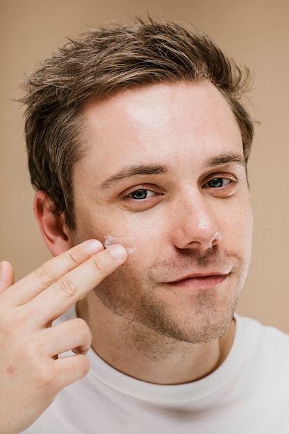 Young man applying facial cream