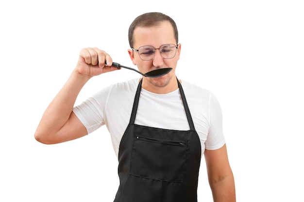 A young man in an apron tries food on a white background Chef or waiter concept mockup