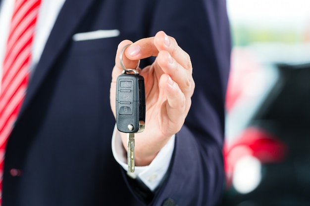 Young man or auto dealer in car dealership