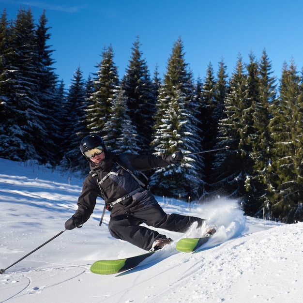 Zaino in spalla del giovane che scia su e giù per i pendii. allenamento dello sciatore maschio nella soleggiata giornata invernale. concetto di sci di fondo.