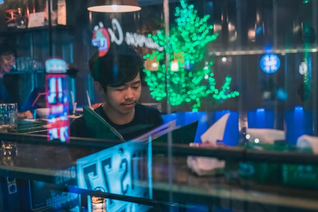 Young man at bar seen through glass during night