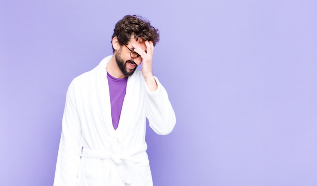 young man in a bathrobe laughing and slapping forehead