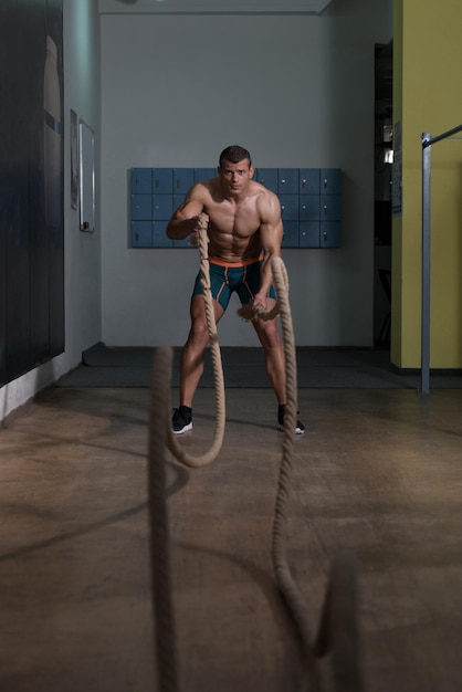 ジムのトレーニング運動でロープと戦う若い男